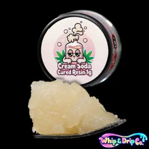 Whip & Drip Co. Cream Soda cured resin concentrate with pale golden extract displayed beside cream soda-themed 1 gram product packaging on a black background.