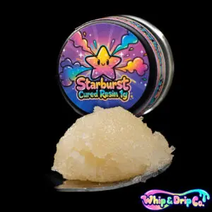“Whip & Drip Co. Starburst cured resin concentrate with golden extract displayed beside colourful candy-themed 1 gram product packaging on a black background.”